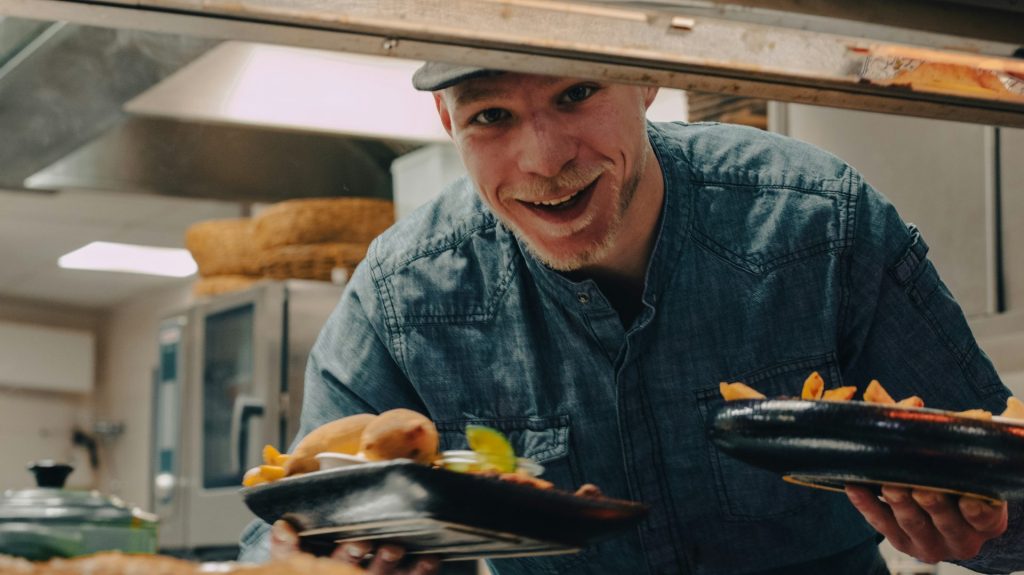 a man holding a plate of food in a kitchen